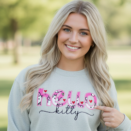 Woman wearing a light gray sweatshirt with 'Bud Kitty' text, standing outdoors.