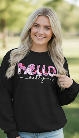 Woman wearing a black sweatshirt with 'hello kitty' text, pointing at it, outdoors.