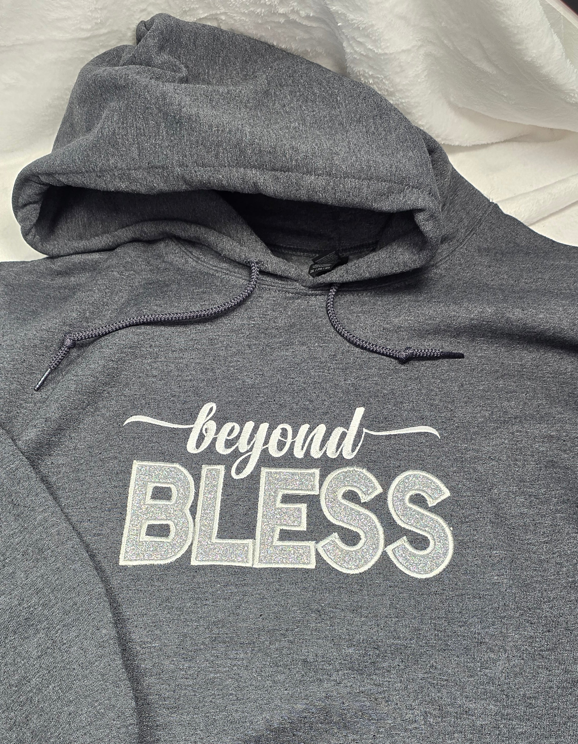 Gray hoodie with 'beyond BLESS' text on a hanger