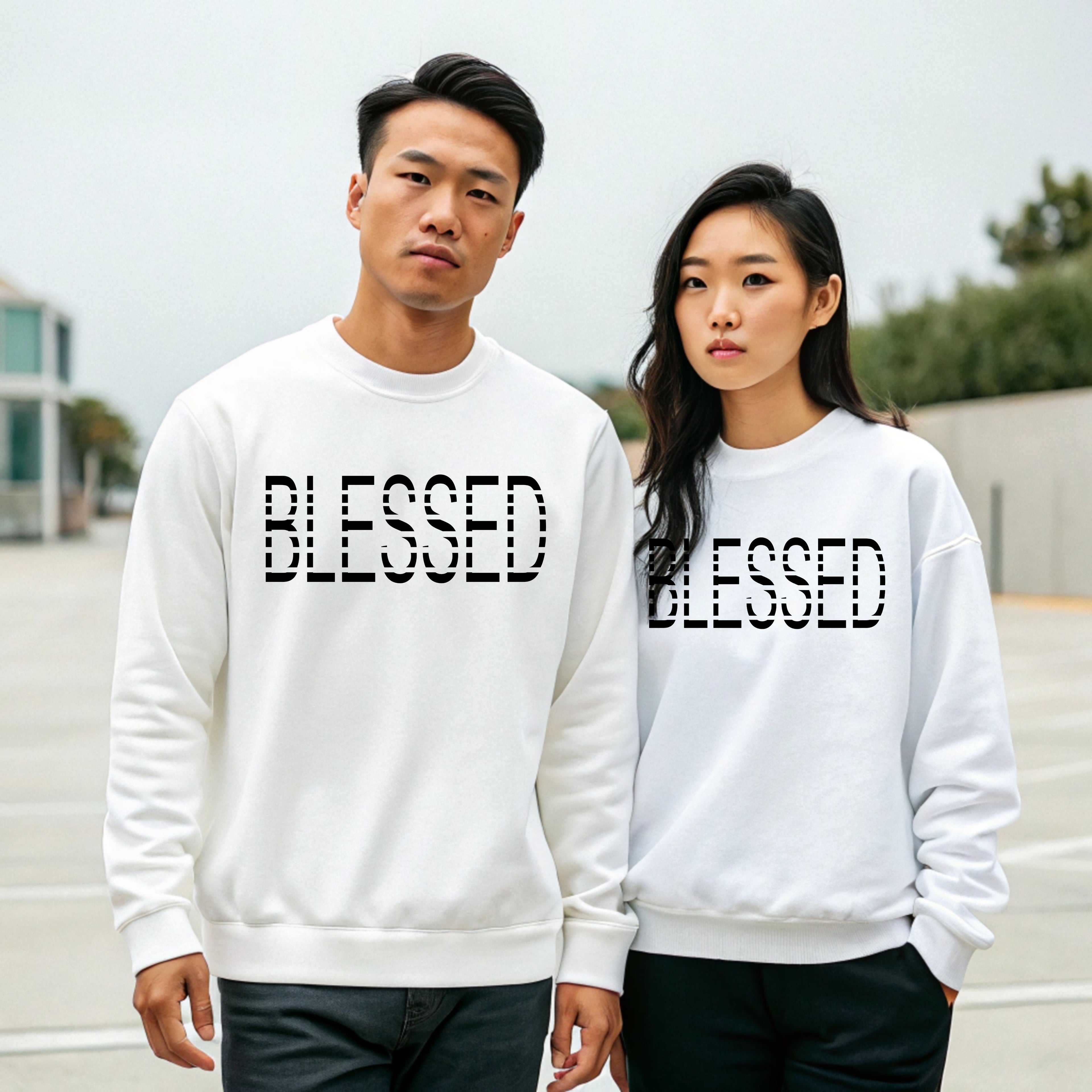 Two people wearing white sweatshirts with 'BLESSED' text outdoors.